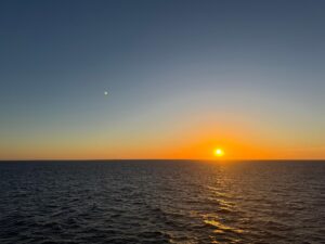 Sun at sunset touching horizon line of ocean