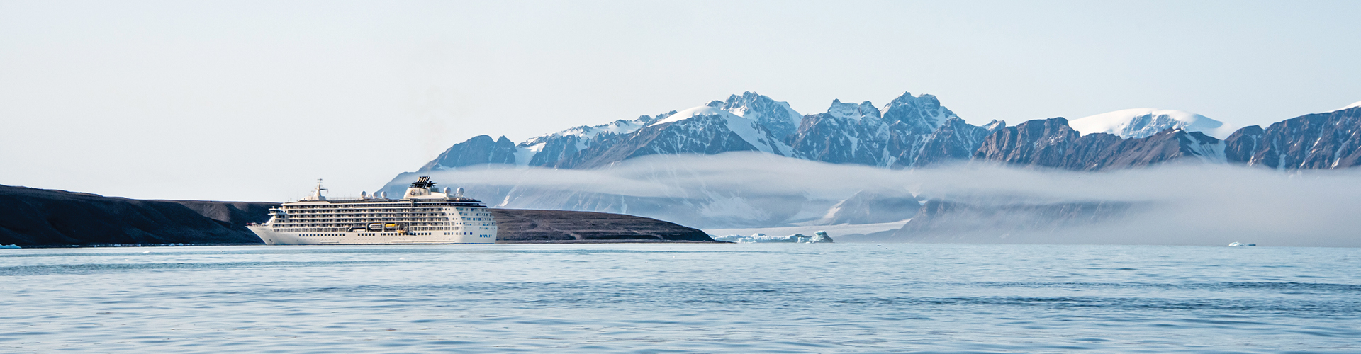 ship in the ocean with glaciers behind it