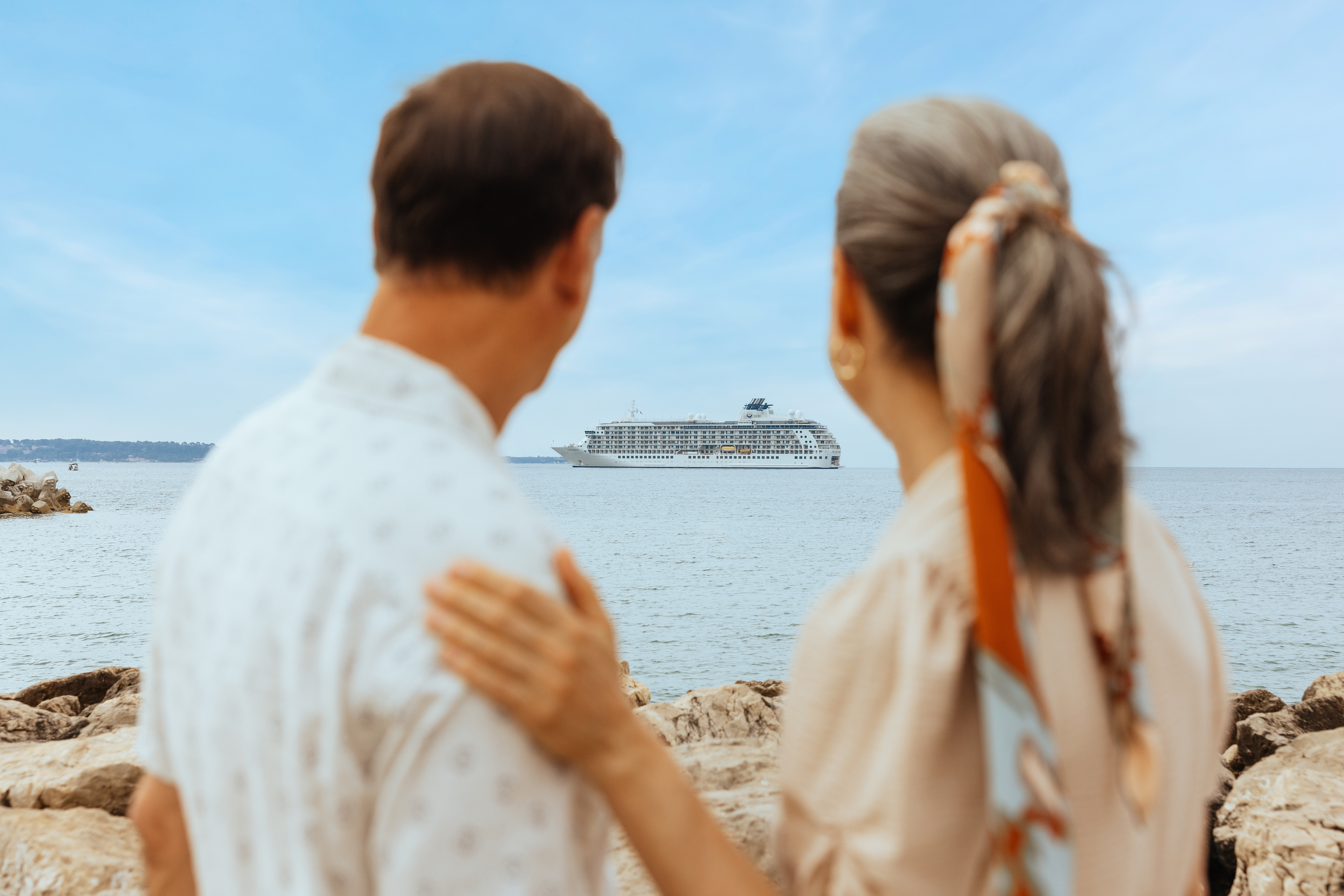 250625_DW_THE-WORLD_01607-RT2.jpg Couple looking at the ship from the beach