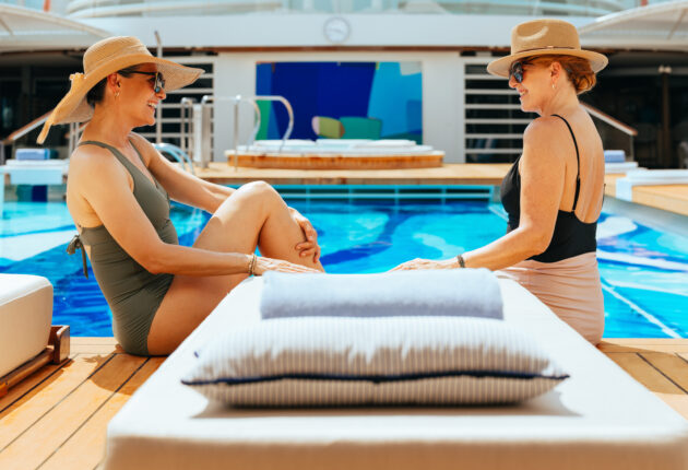 two woman smiling at each other by the pool